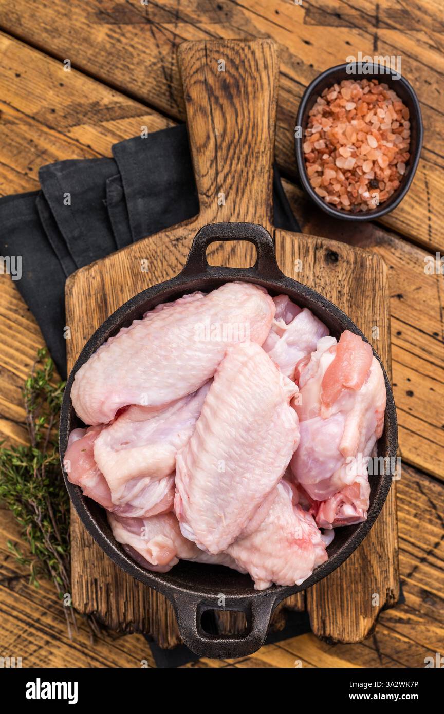 Succose ali ali di pollo crude, un ingrediente versatile perfetto per friggere, cuocere o grigliare alla perfezione. sfondo in legno. vista dall'alto. Foto Stock
