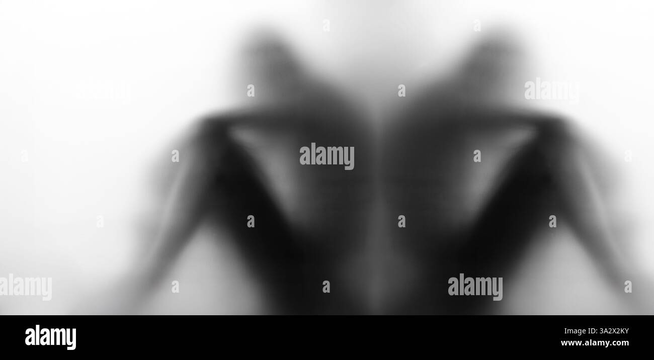 Una rappresentazione in bianco e nero visivamente sorprendente di una figura ombrosa e senza volto in posizione seduta, che crea un'aura di mistero e profonda introspezione. Foto Stock