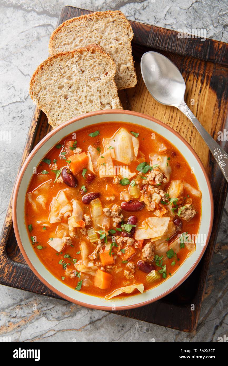 Zuppa di cavolo di manzo macinato, con fagioli rossi, cipolla, pomodori, carote e sedano nel piatto sul tavolo. Vista dall'alto verticale Foto Stock