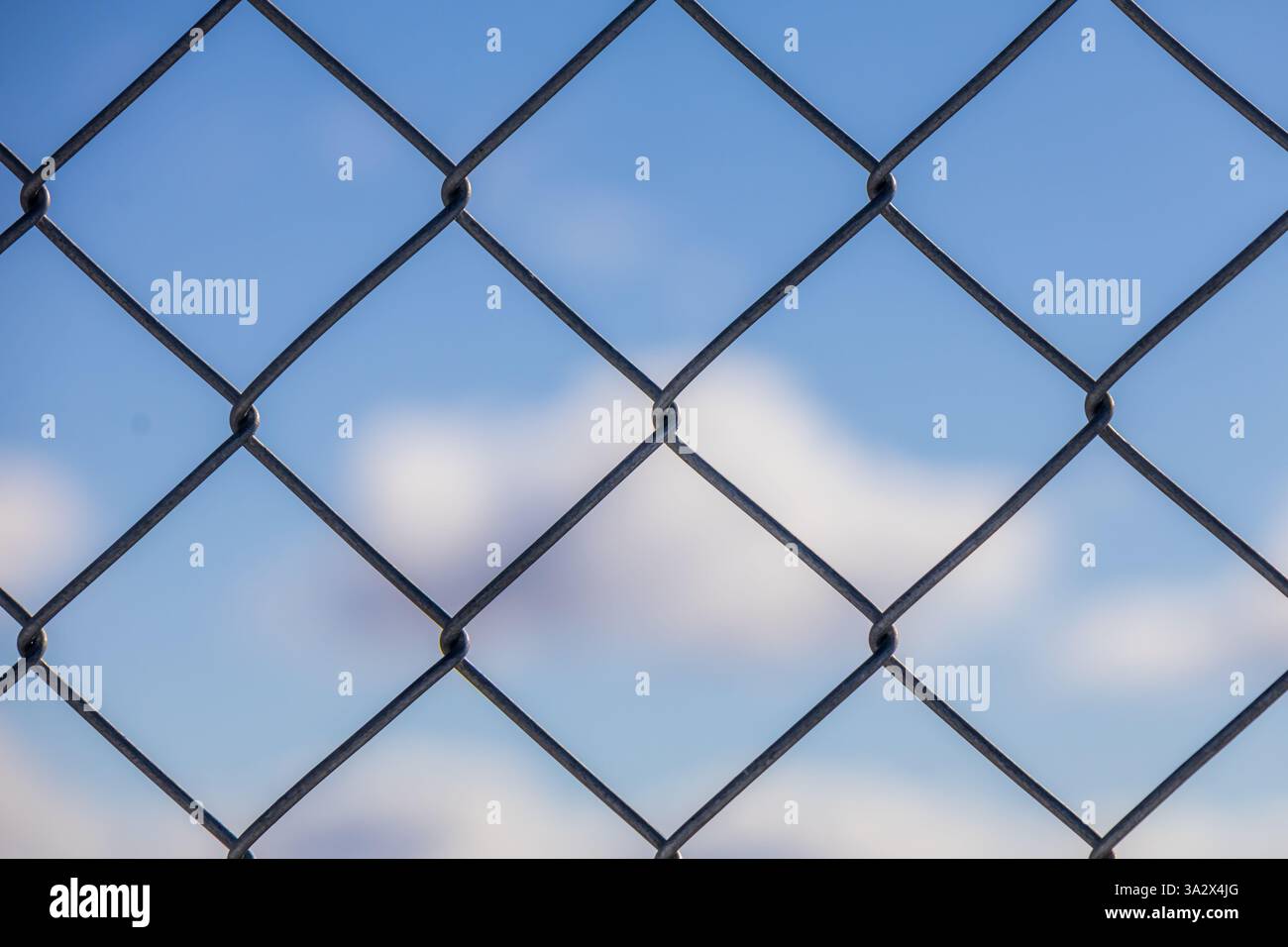 la recinzione a filo avvolge un cielo blu nuvoloso con particolare attenzione alla recinzione Foto Stock