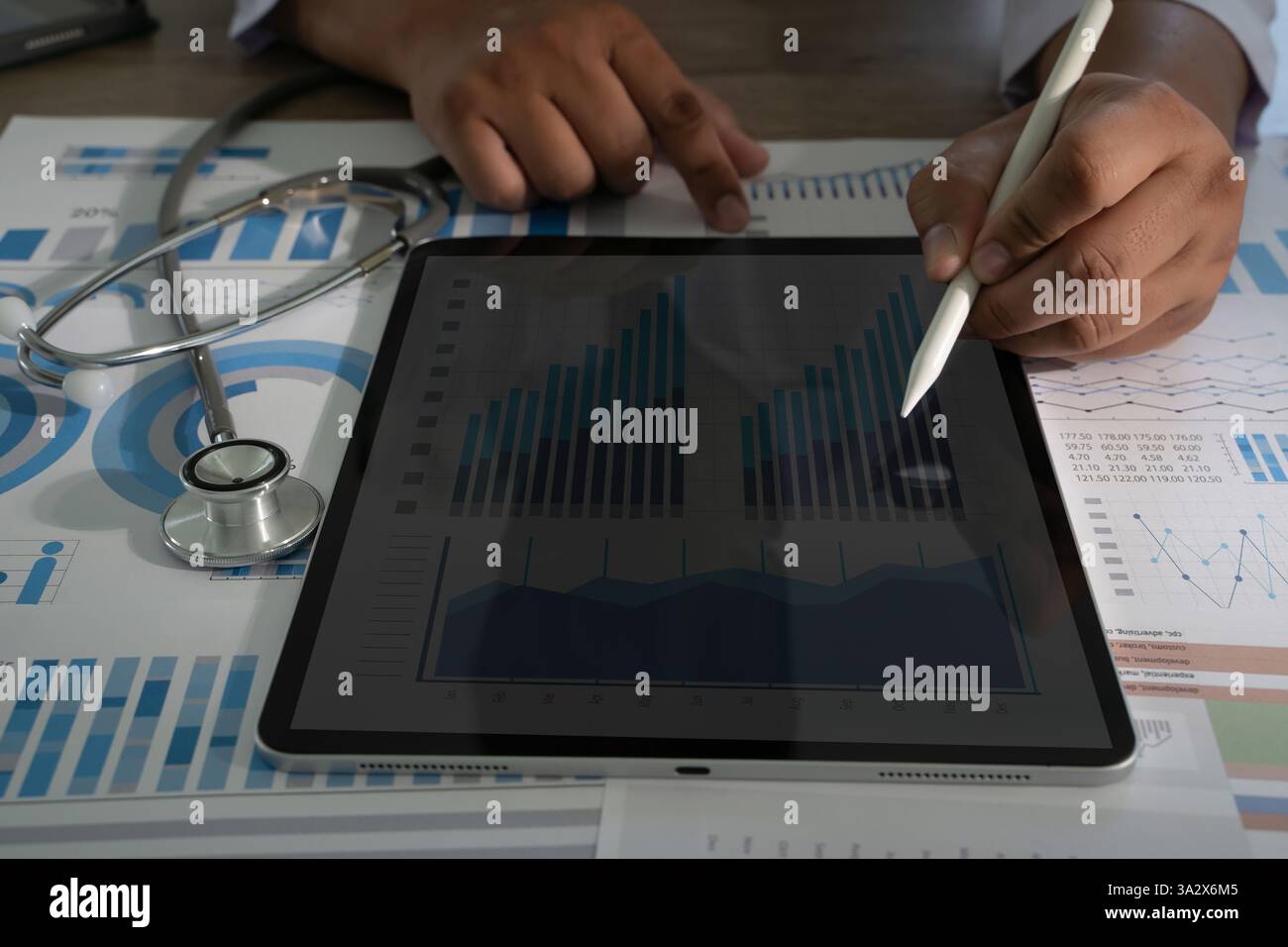 Il medico utilizza la tecnologia moderna e l'analisi medica per migliorare la cura dei pazienti. Ricerca sul lavoro medico monitoraggio con stetoscopio e grafici Foto Stock