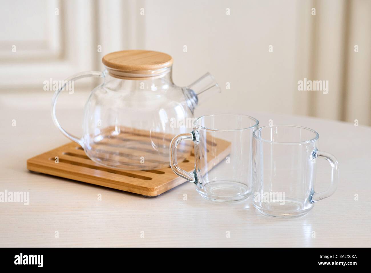 Piatti ecologici. Svuotare la tazza di vetro e la teiera con coperchio in legno sul tappetino in vimini Foto Stock