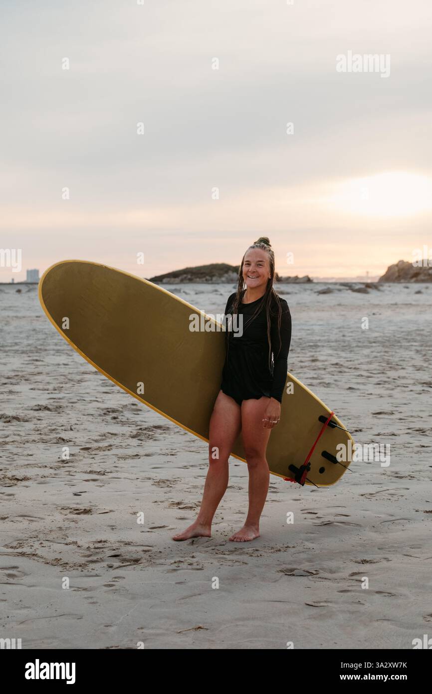 Una surfista millenaria posa con la sua tavola sulla spiaggia di S. Foto Stock