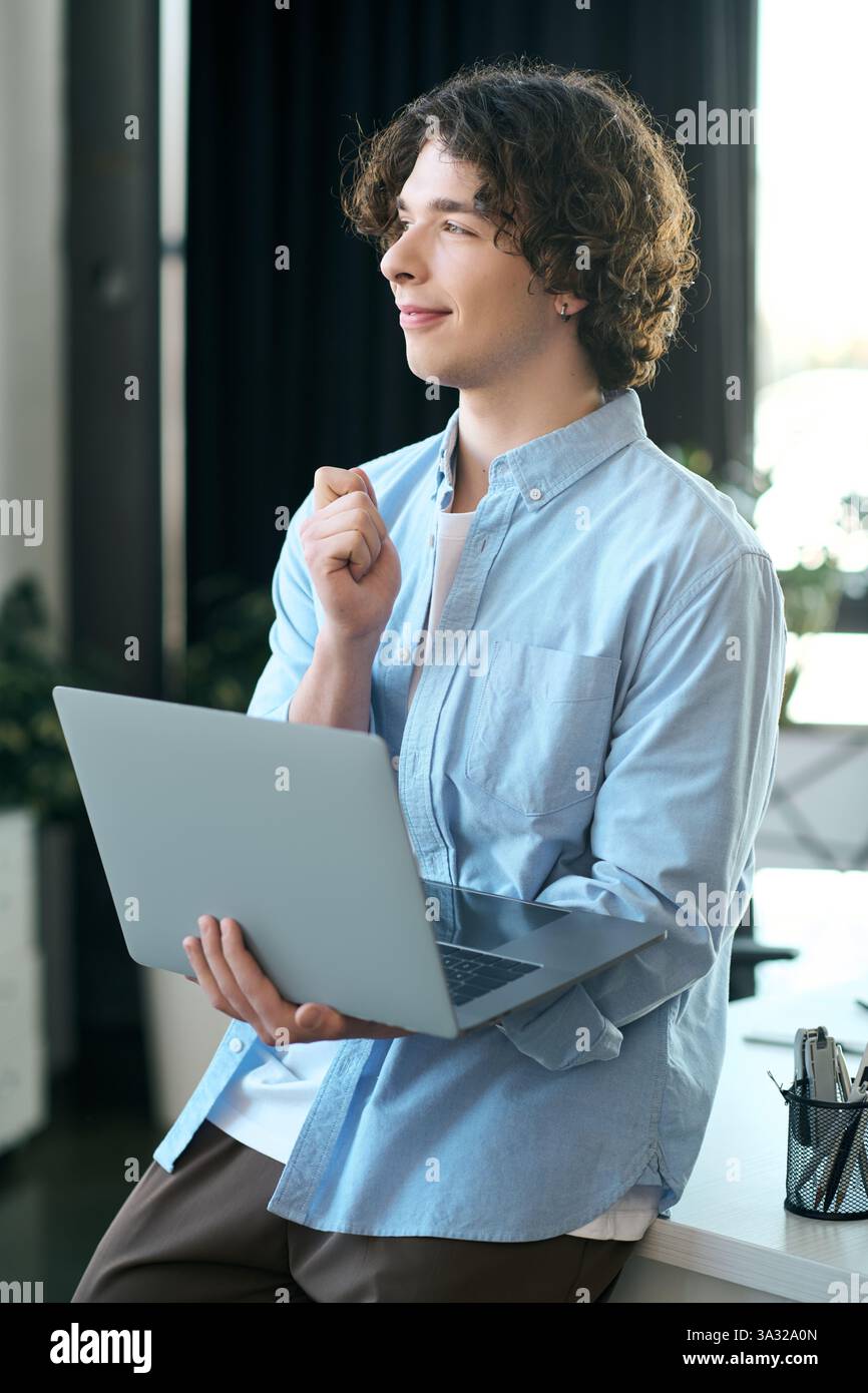 Un uomo giovane e attraente, in un ambiente di ufficio elegante, si impegna in un lavoro attento con un notebook. Foto Stock