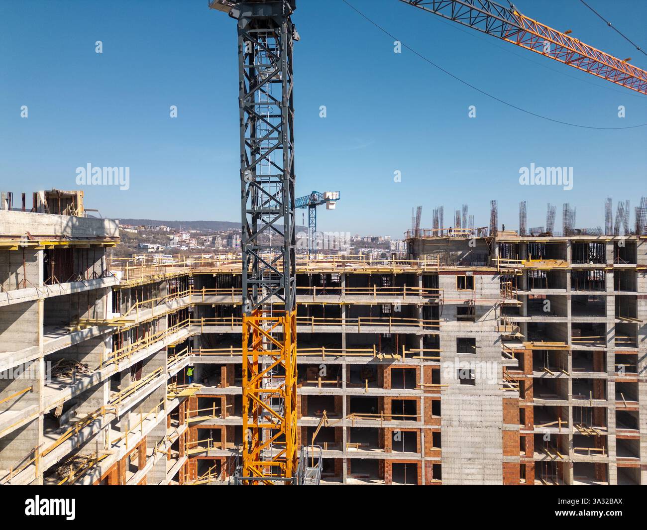 Cantiere di un alto edificio nelle giornate di sole. La struttura in cemento, le gru e le impalcature della struttura sono immerse nella luce solare Foto Stock
