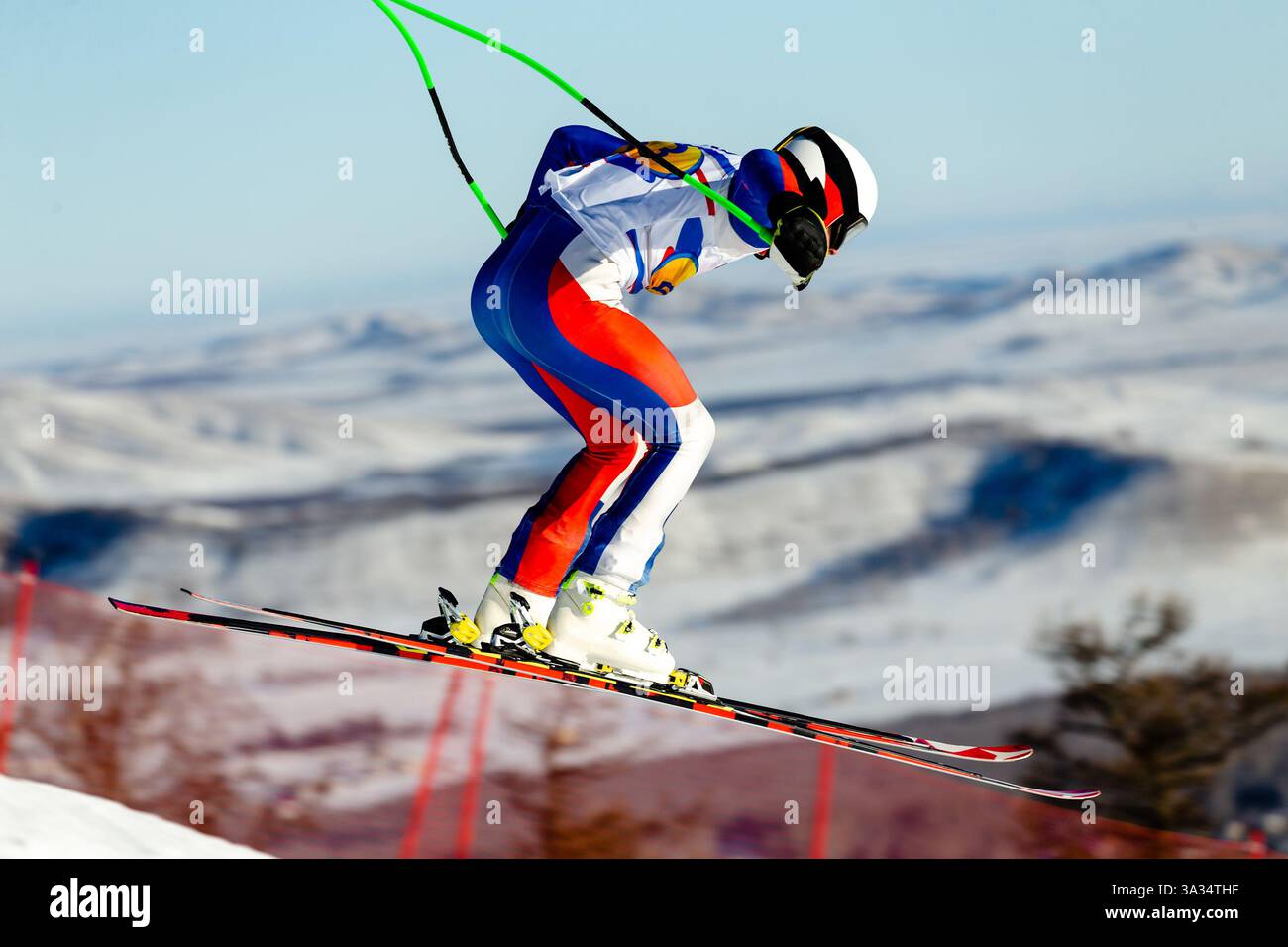gli sciatori eseguono salti durante lo sci alpino competitivo in un paesaggio innevato di montagna Foto Stock