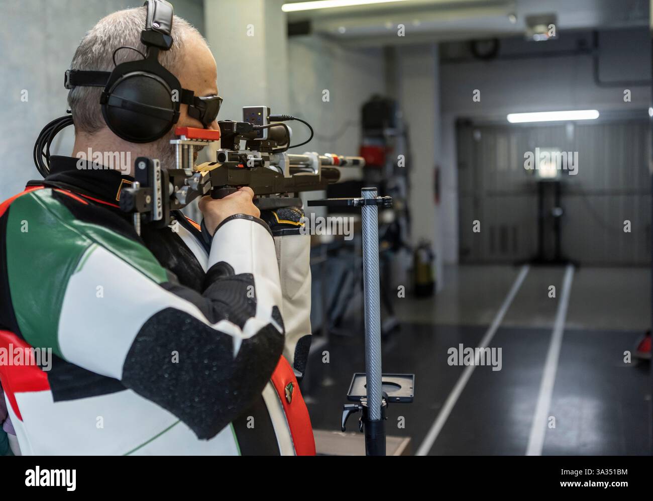 Un atleta cieco pratica sparando su una gamma in stile olimpico, mostrando concentrazione e determinazione. L'attrezzatura adattiva viene utilizzata per favorire la precisione e l'enha Foto Stock
