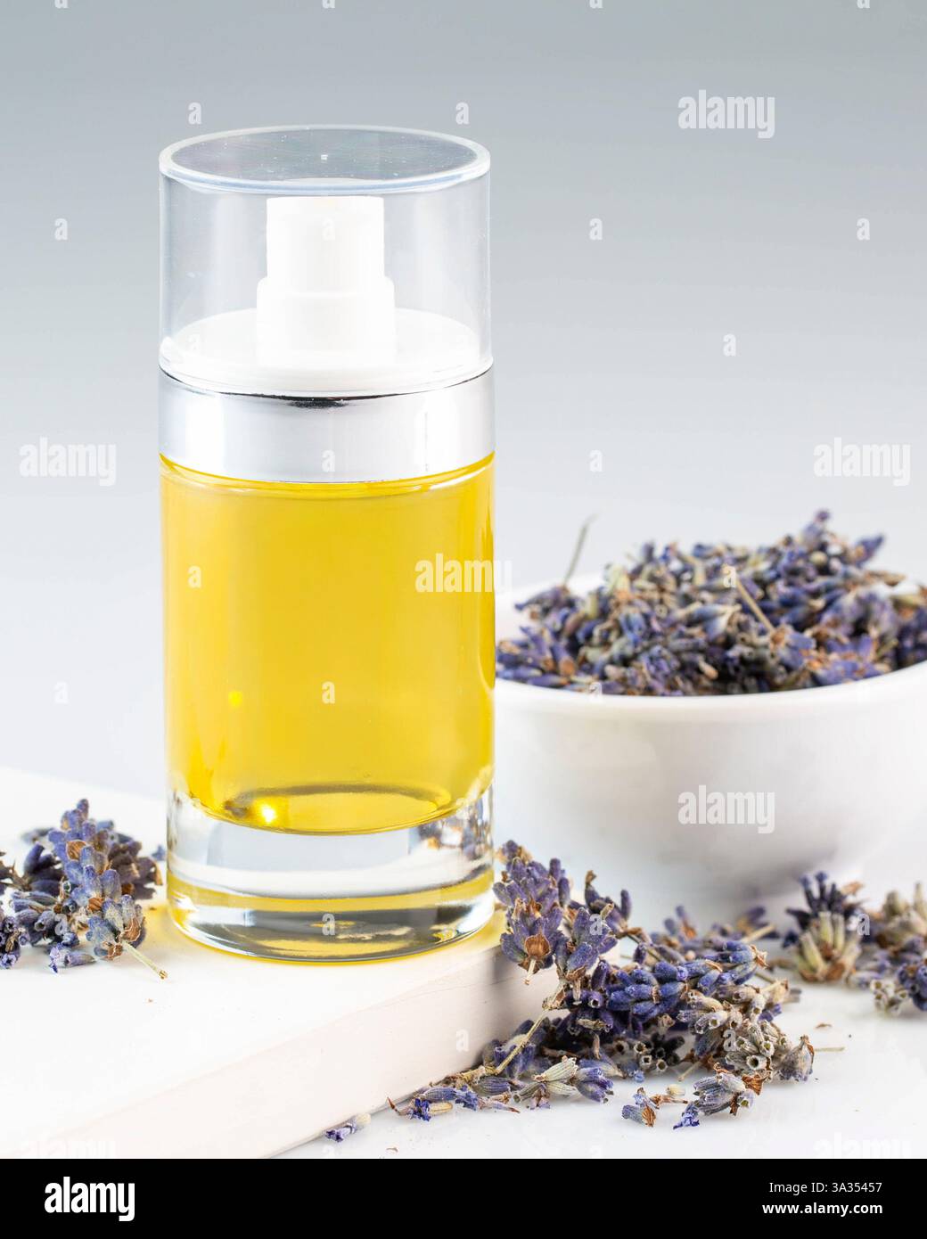 Una bottiglia di vetro riempita con olio di lavanda si trova accanto ai fiori secchi di lavanda. L'essenza rilassante della lavanda evoca relax e calma, perfetto per la vostra vacanza Foto Stock