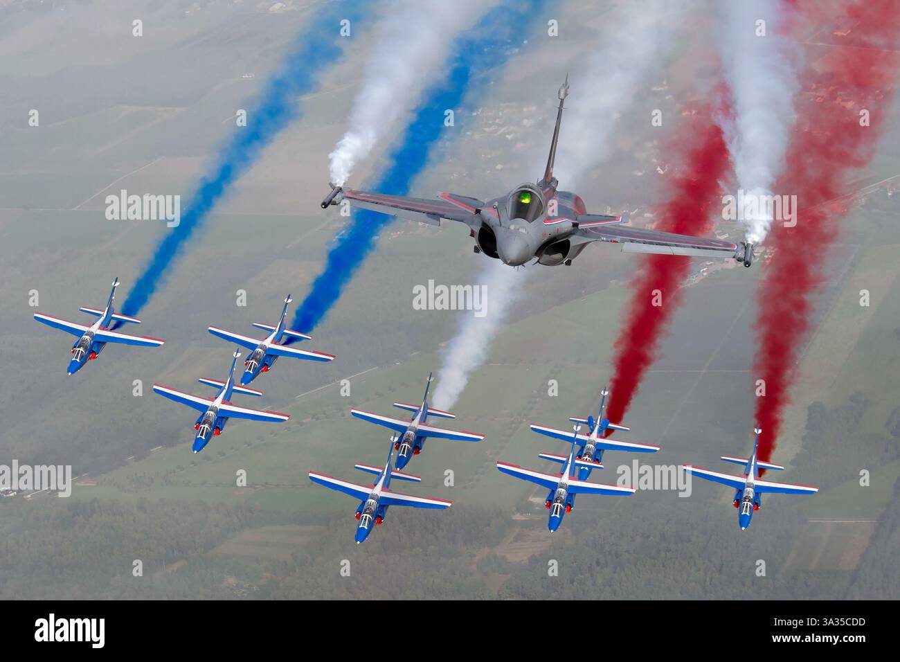 L'aeronautica e spaziale francese Dassault Rafale C, 4-C1, vola in formazione con l'Alpha Jet, mostrando la vernice da esposizione della Patrouille de France. L'aereo emette fumo rosso, bianco e blu come parte di una esibizione aerea, celebrando l'aviazione francese. Foto Stock