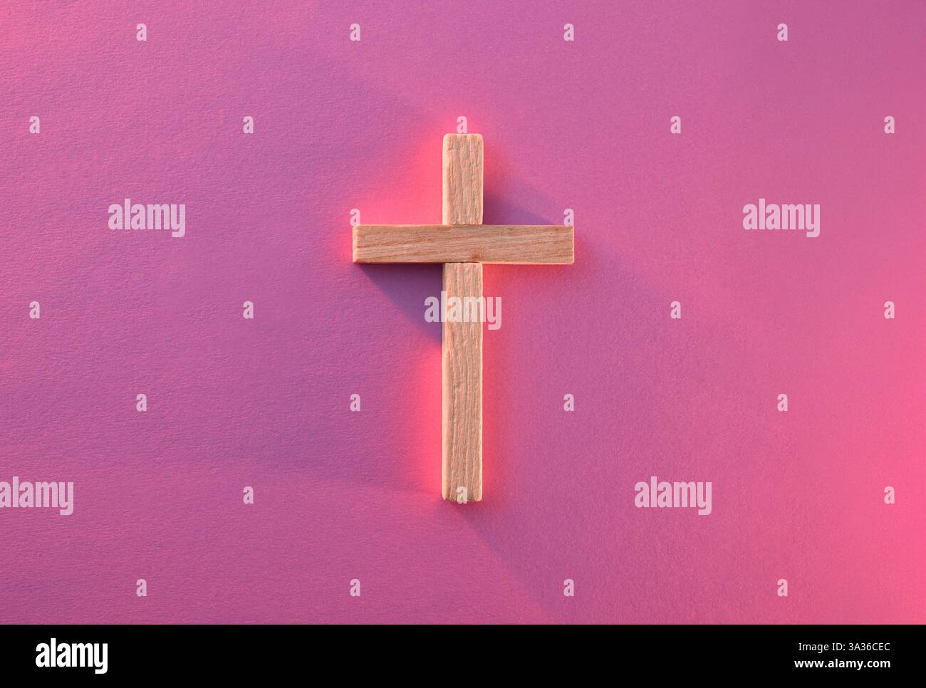 Sfondo con croce cristiana in legno illuminata con luce rossa isolata al centro su una base viola. Vista dall'alto. Foto Stock