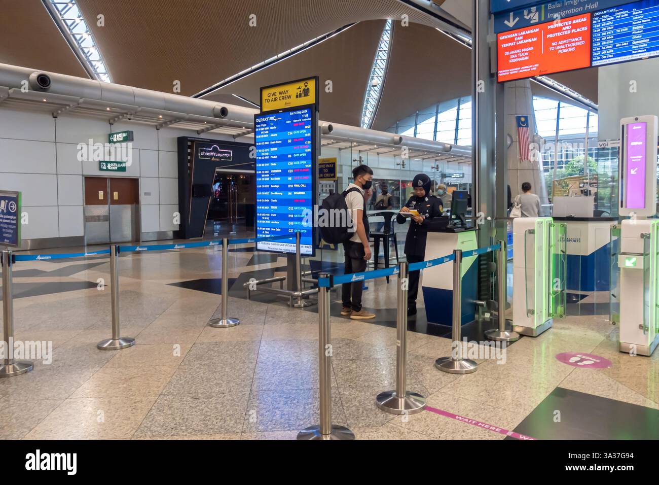 Area check-in all'Aeroporto Internazionale di Kuala Lumpur (KLIA) in Malesia. Passeggeri ai banchi di check-in, informazioni sul volo, controllo del personale femminile Foto Stock