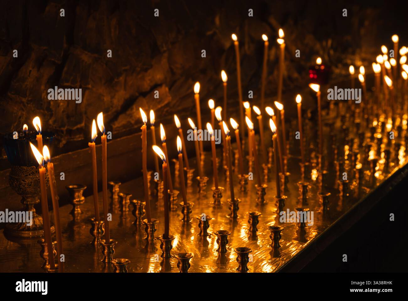 Le candele accese si illuminano poco in un ambiente sereno e religioso che crea un'atmosfera di spiritualità e tranquillità. Foto Stock
