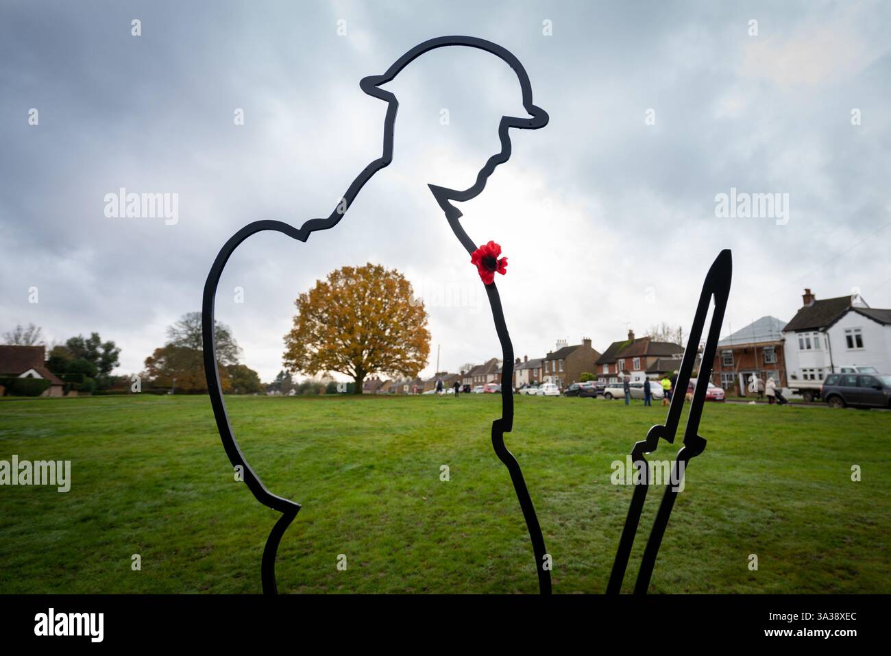 Il profilo di un soldato che commemora il giorno della memoria si erge sul verde del villaggio con papavero Foto Stock
