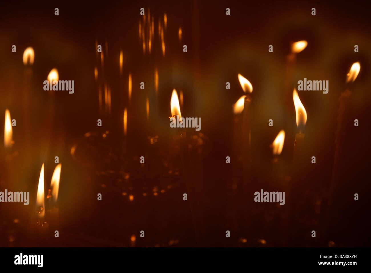 Piccole candele che si illuminano con calore su uno sfondo nebbioso scuro, evocano sentimenti di spiritualità, serenità e riflessione, ideali per temi di pace e Foto Stock