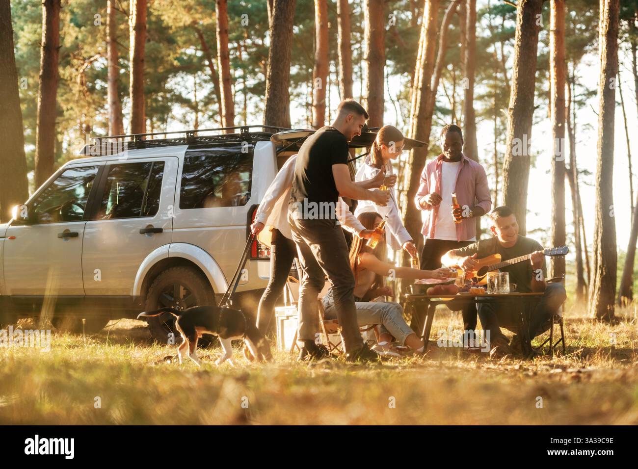 Divertirsi vicino alla macchina. Un gruppo di amici si diverte insieme nella foresta. Foto Stock