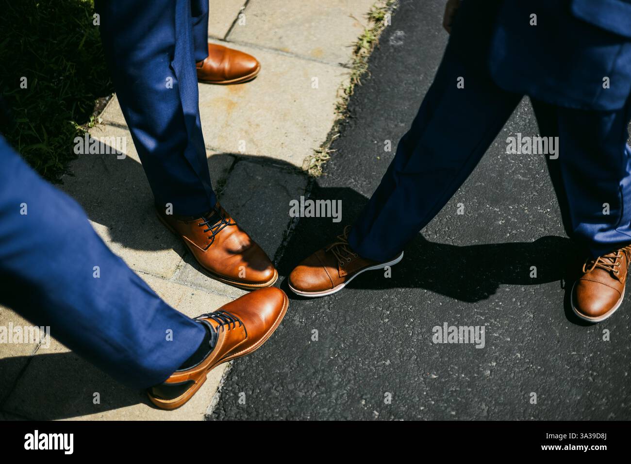 Primo piano dei piedi di tre persone, con un piede che si sposta in avanti e tocca le dita degli altri due, simboleggiando la connessione e l’unità. Foto Stock