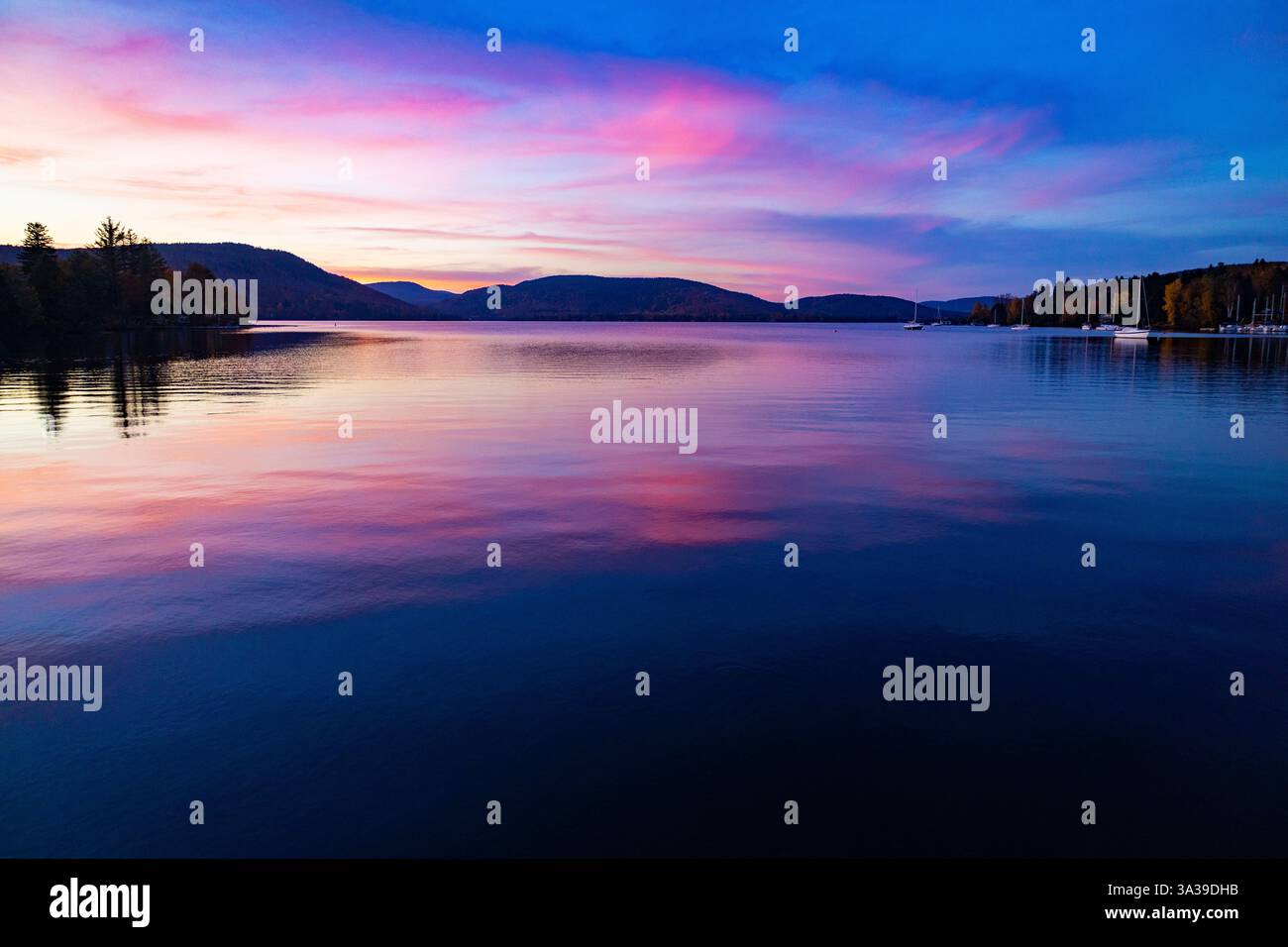 Uno splendido tramonto con vivaci sfumature viola, rosso e giallo che riempiono il cielo. I colori caldi si fondono insieme, creando una vista mozzafiato durante il giorno Foto Stock