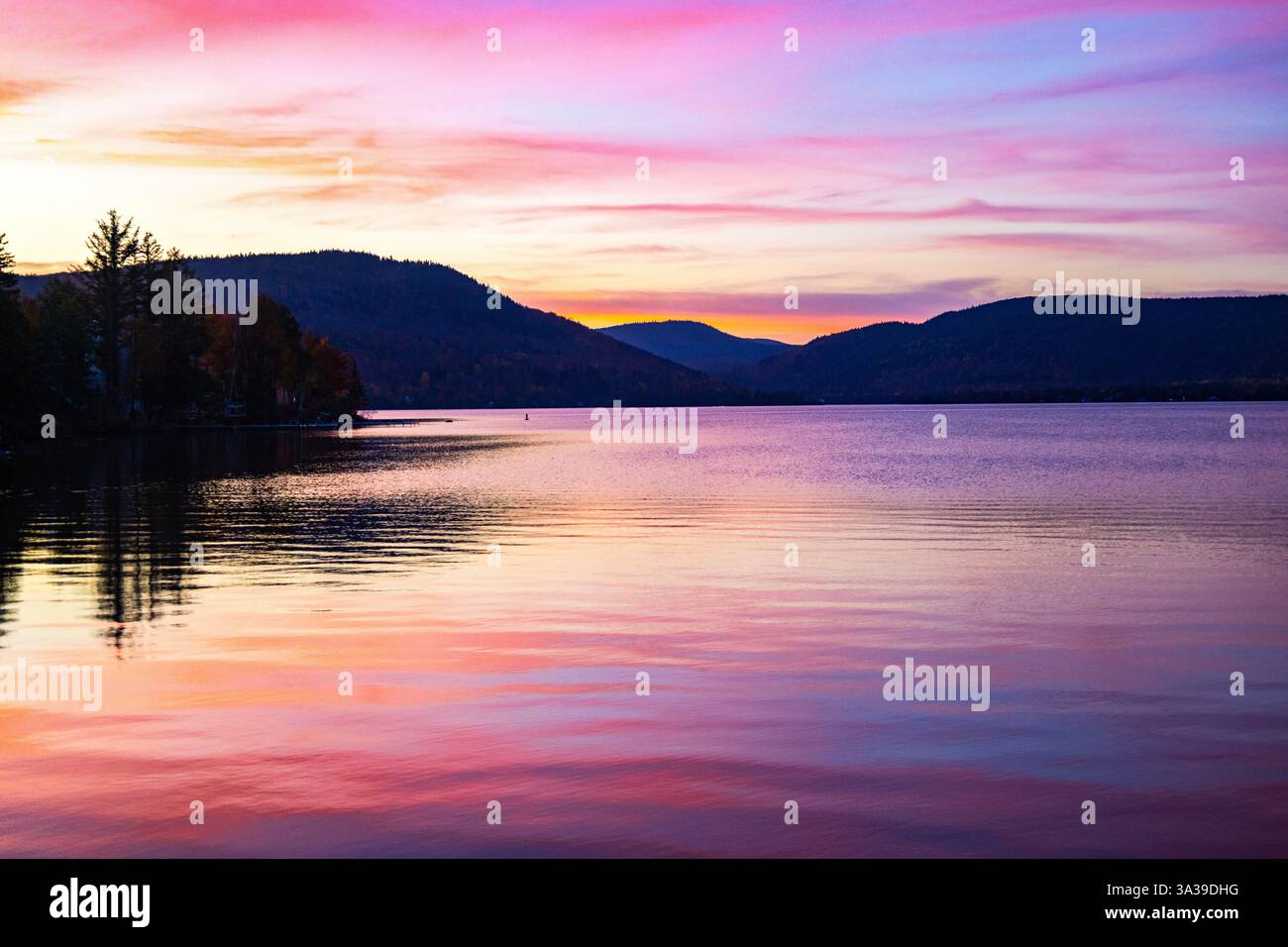 Uno splendido tramonto con vivaci sfumature viola, rosso e giallo che riempiono il cielo. I colori caldi si fondono insieme, creando una vista mozzafiato durante il giorno Foto Stock