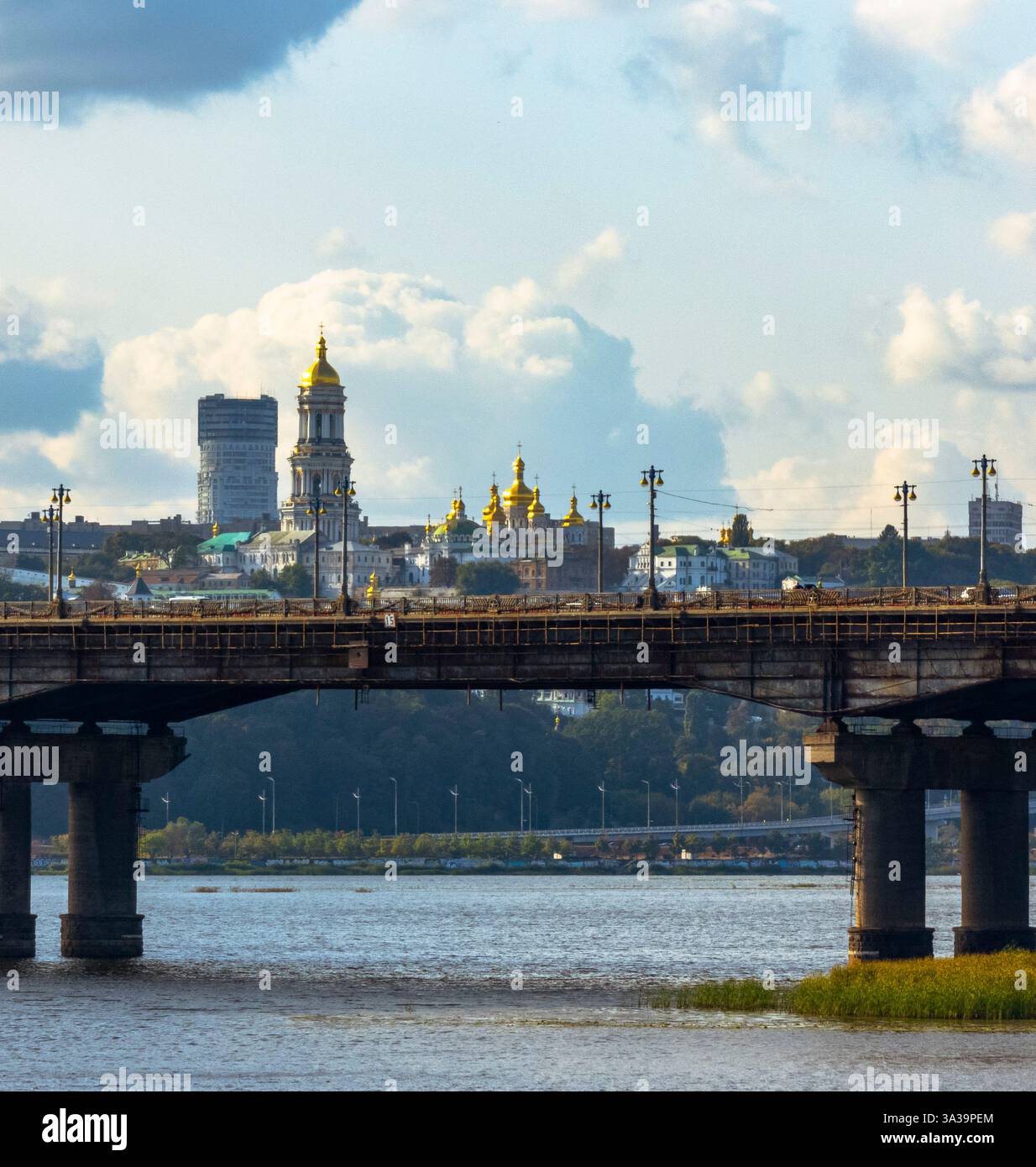 Le guglie dorate di una maestosa cattedrale si stagliano sullo sfondo, con un ponte che collega la vivace vita urbana e le acque serene sotto un cielo dipinto. Kiev pechersk lavra , antico monastero ucraino Foto Stock
