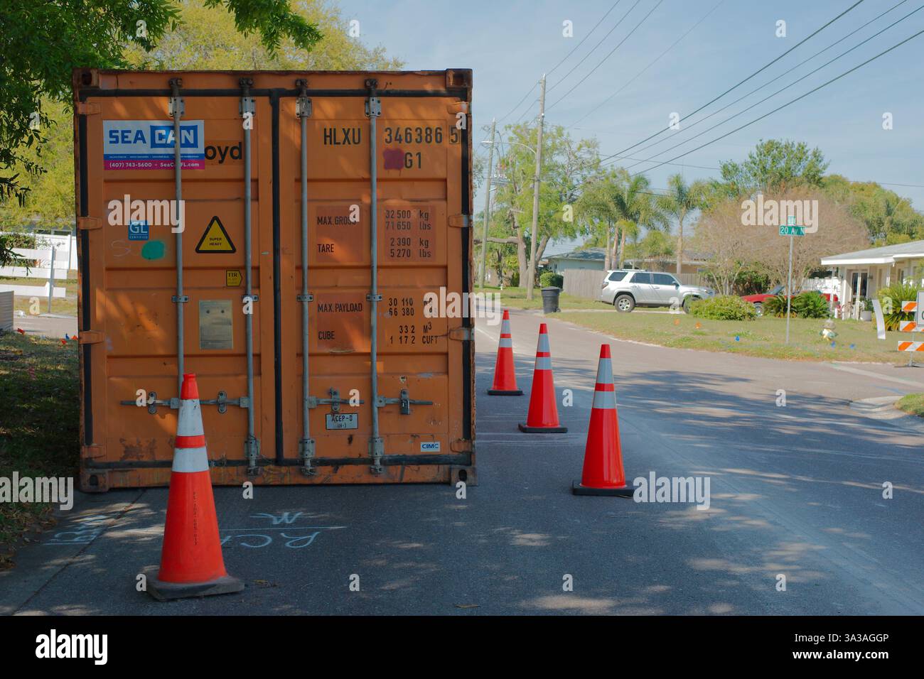 Scena stradale con un grande container arancione posizionato sul lato della strada che blocca parzialmente il traffico. Solo per uso editoriale 14 marzo 2025 S. Foto Stock