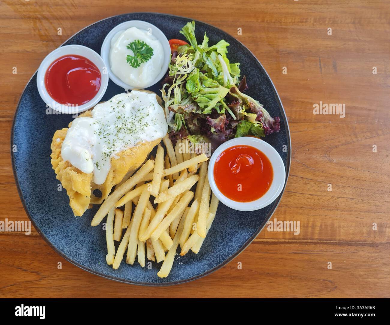 Pesce e patatine fritte con contorni di insalata e salsa di tartaro. Foto Stock