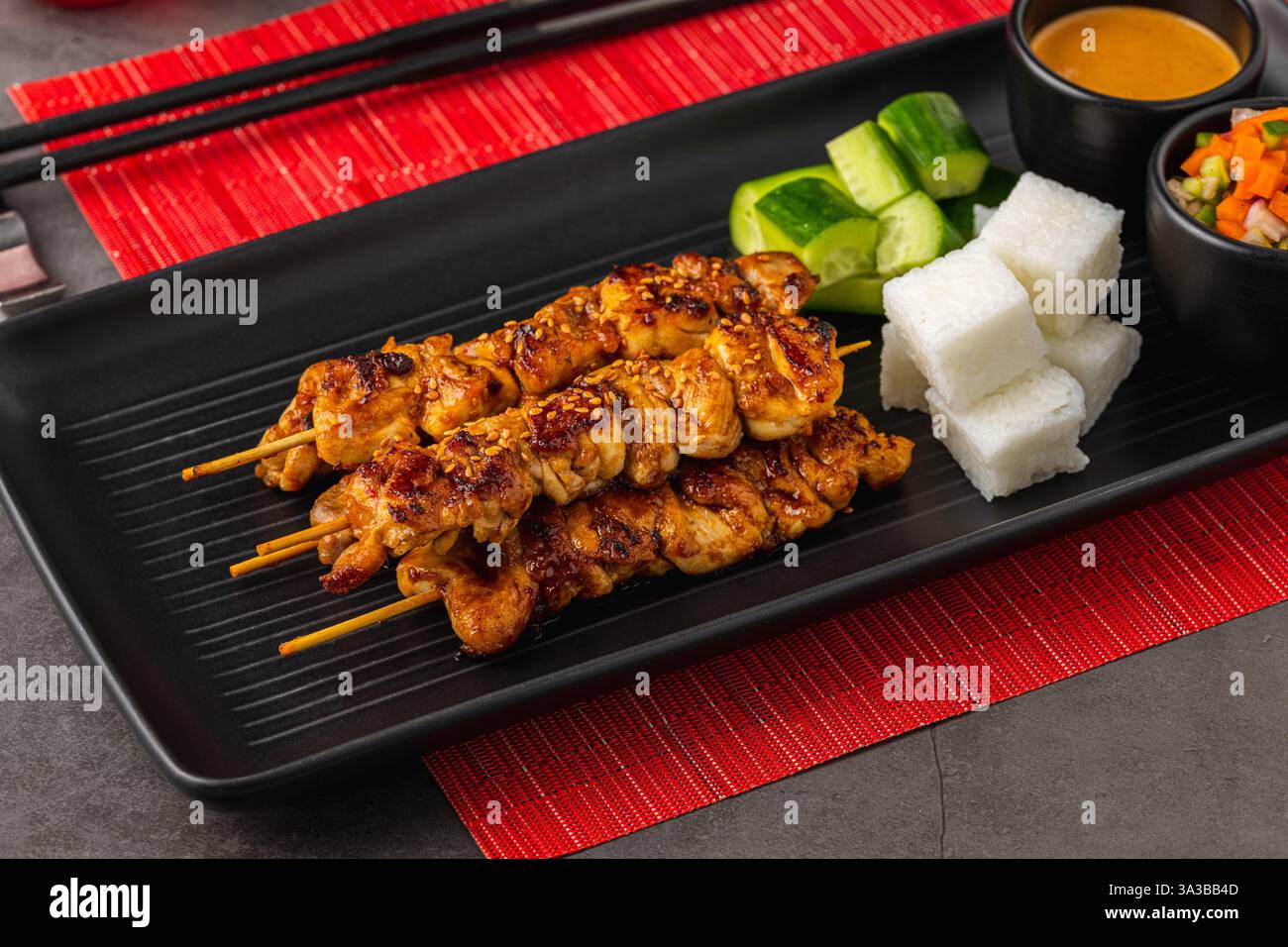 Spiedini satay di pollo alla griglia con salsa di arachidi, torte di riso e verdure Foto Stock