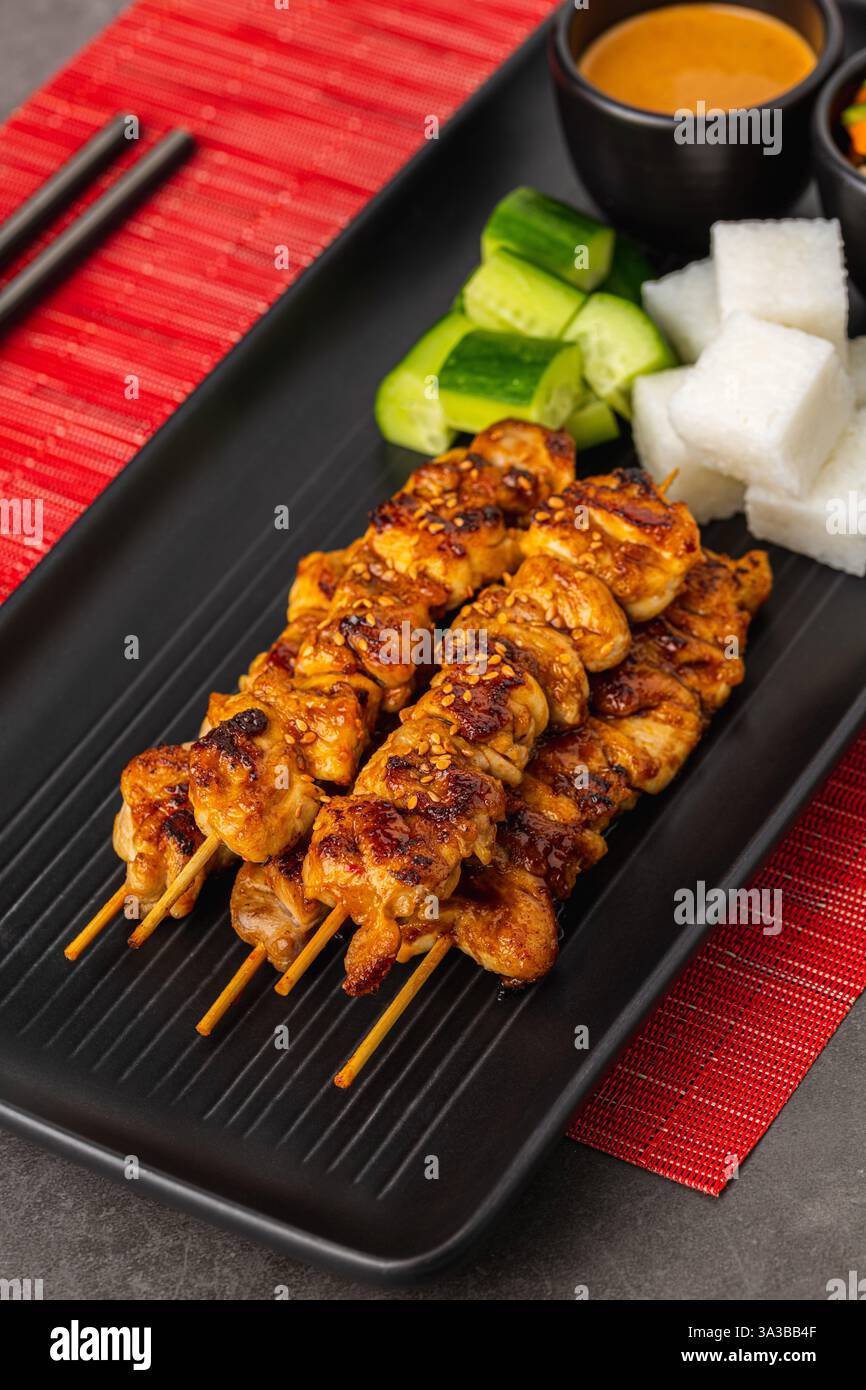 Spiedini satay di pollo alla griglia con salsa di arachidi, torte di riso e verdure Foto Stock