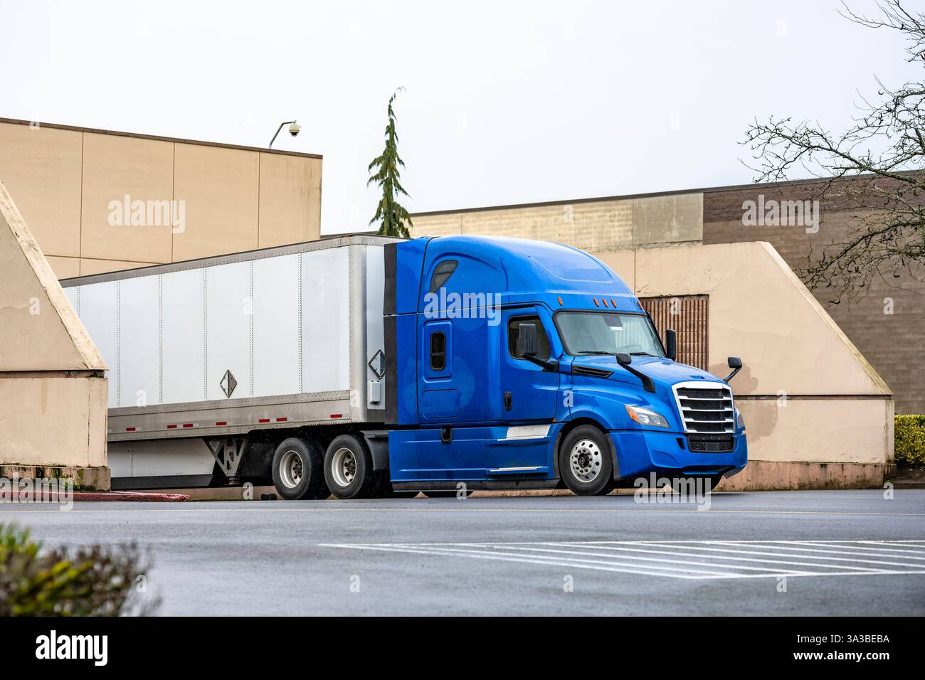Semi-camion di lunga percorrenza blu grande carro industriale con cabina estesa per il riposo del conducente del veicolo e scarico semi-rimorchio di furgoni asciutti consegnato in posizione di carico Foto Stock