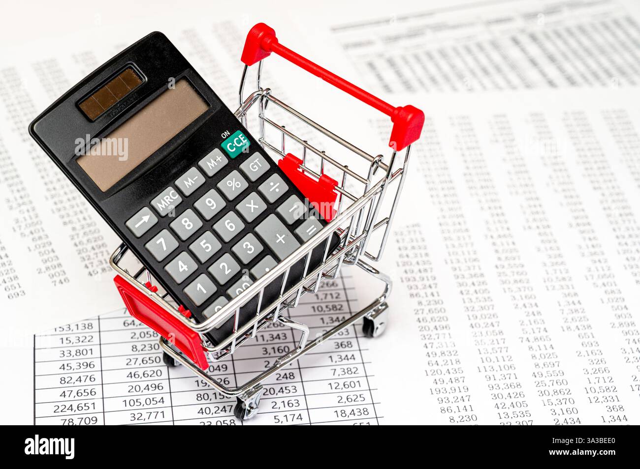 Carrello della spesa con calcolatrice e monete sui documenti finanziari Foto Stock