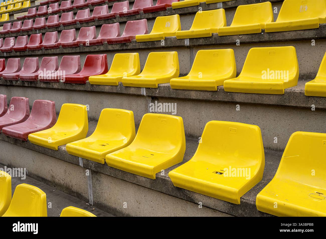 Sedili in plastica gialla e rossa in uno stadio sportivo senza persone Foto Stock