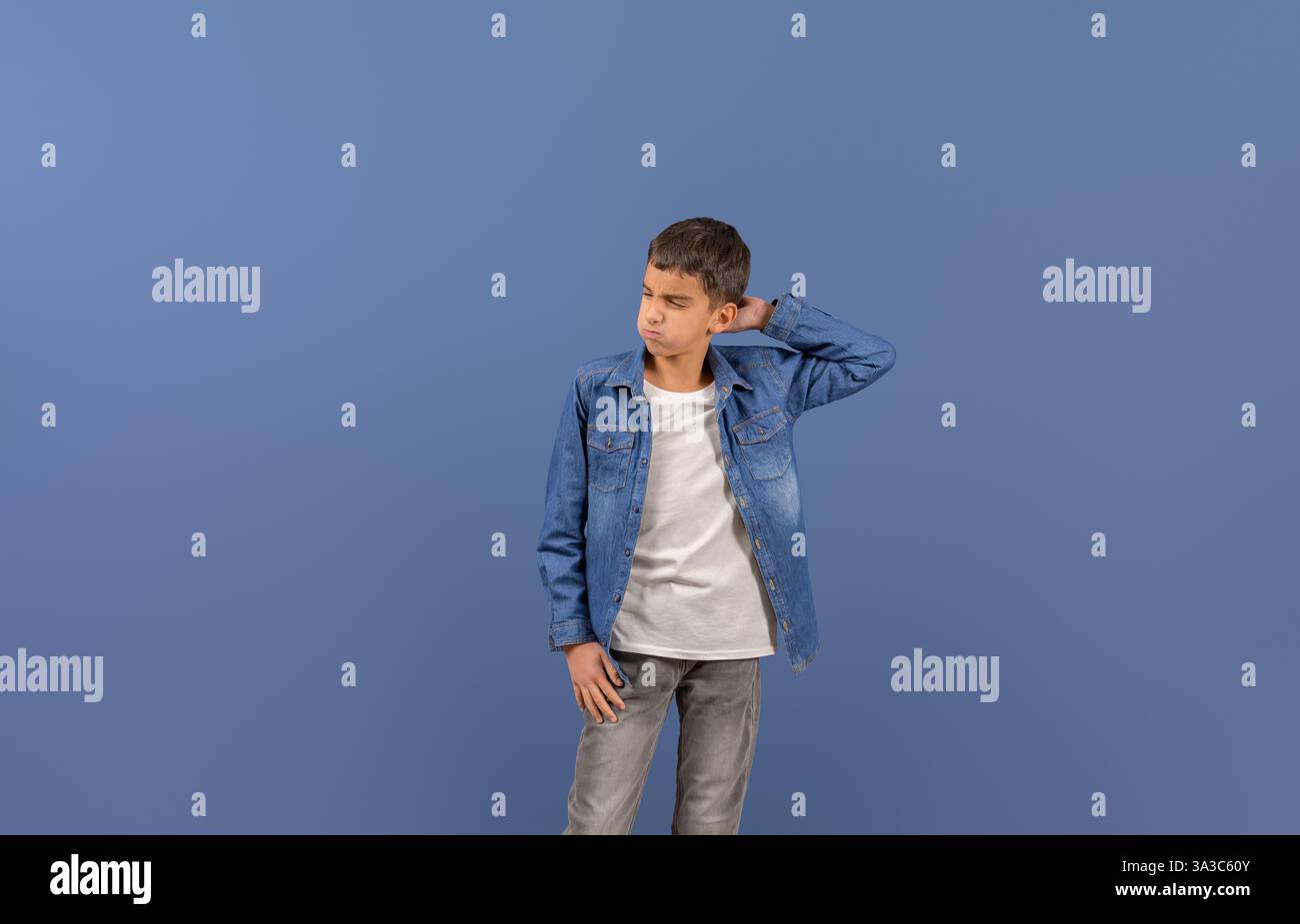 Giovane uomo d'affari dall'espressione frustrata che gratta la testa mentre si trova su sfondo blu Foto Stock