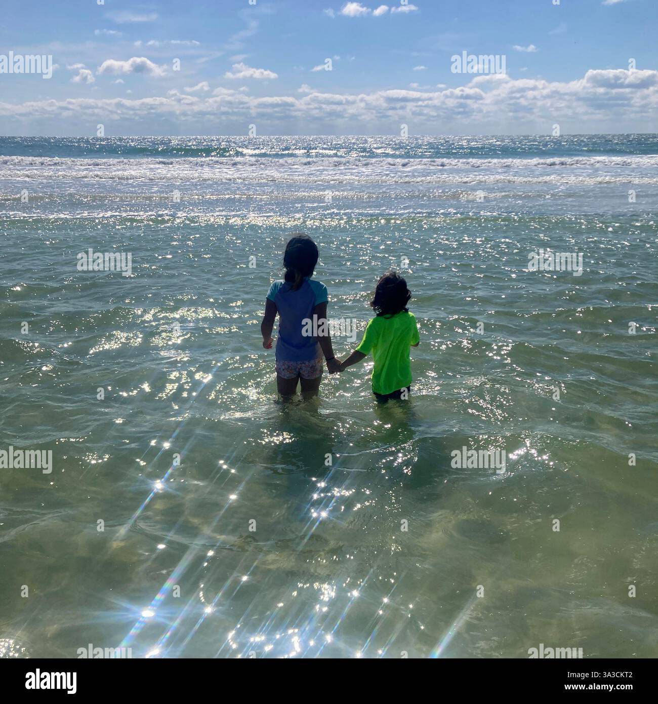 I bambini si aggrappano l'un l'altro mentre si immergono nell'oceano a Anna Maria Island, Florida, Stati Uniti Foto Stock