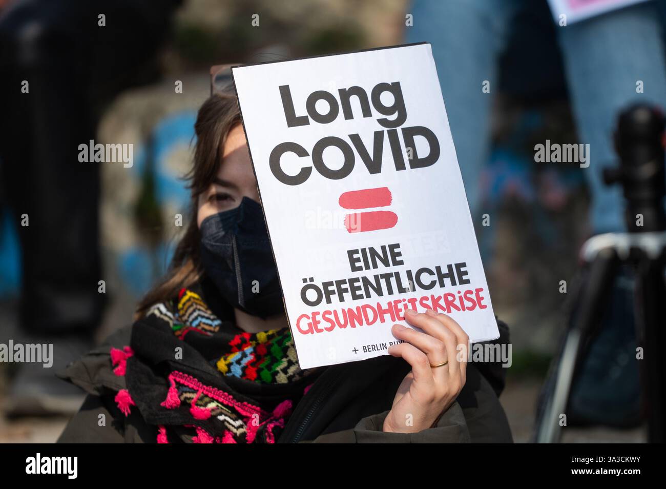 Berlino, Germania. 15 marzo 2025. Una donna tiene un poster con le parole "Long Covid = una crisi sanitaria pubblica" in occasione di una manifestazione per la "giornata internazionale della sensibilizzazione lungo Covid". La giornata ha lo scopo di richiamare l'attenzione sui problemi affrontati dalle persone che soffrono dei vari sintomi di Long Covid. Crediti: Christophe Gateau/dpa/Alamy Live News Foto Stock