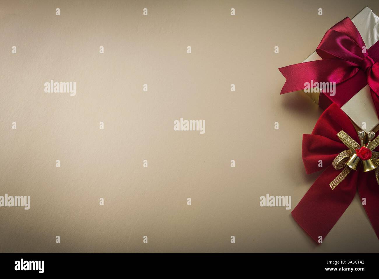 Confezione regalo avvolta con un'inchino su sfondo dorato per le festività Foto Stock