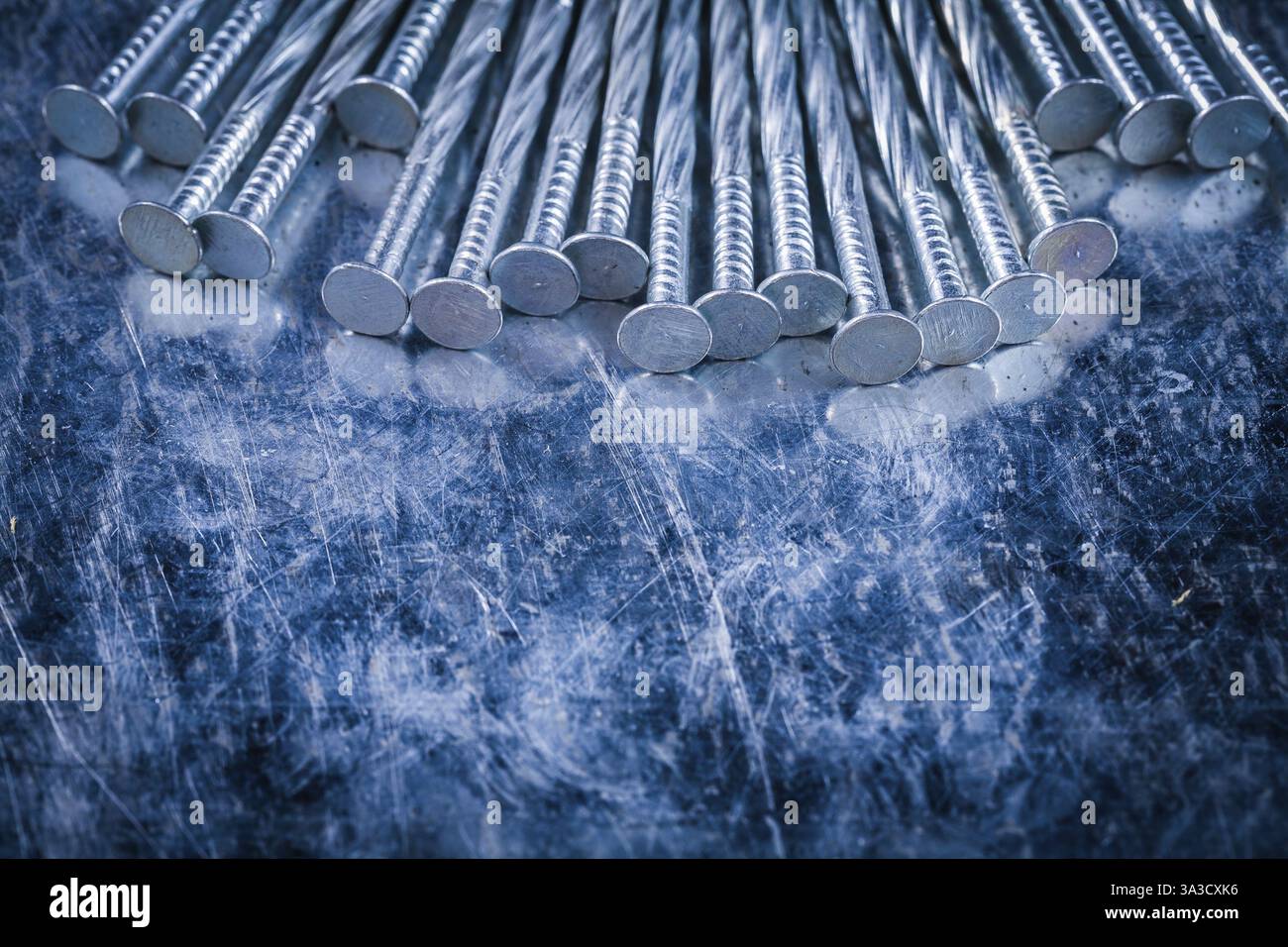 Pila di chiodi in metallo su sfondo metallico graffiato Copia spazio immagine concetto di costruzione Foto Stock