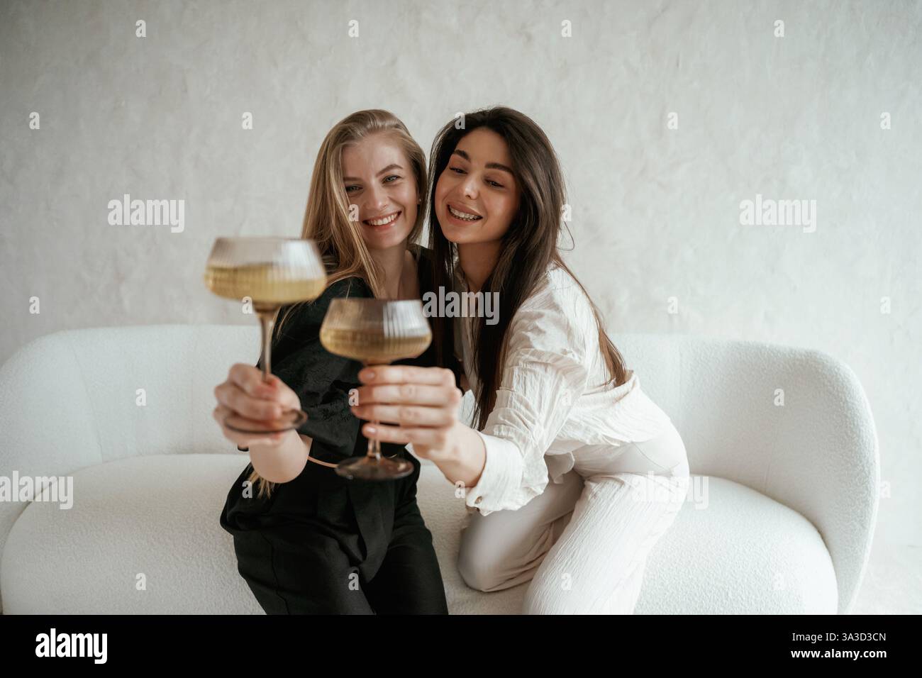 In bianco e nero, con drink, festeggiando. Due giovani amiche felici sono al chiuso. Foto Stock