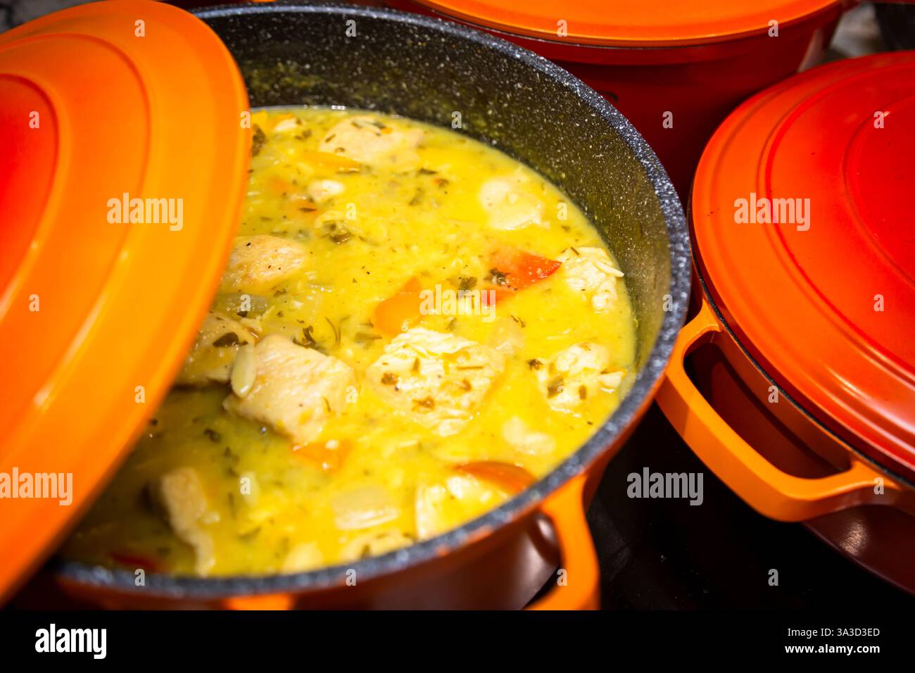 Cottura della carne di maiale in una salsa in una pentola di ferro pesante Foto Stock