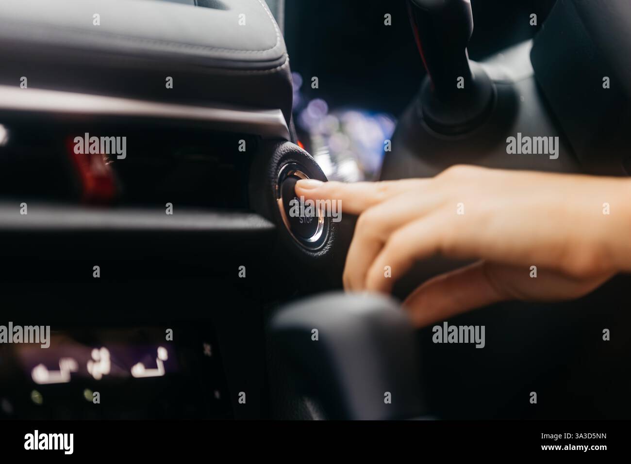 Primo piano di un pulsante di avviamento della vettura premuto da una donna. Concetto di tecnologia moderna, convenienza e innovazione nelle auto. Foto Stock