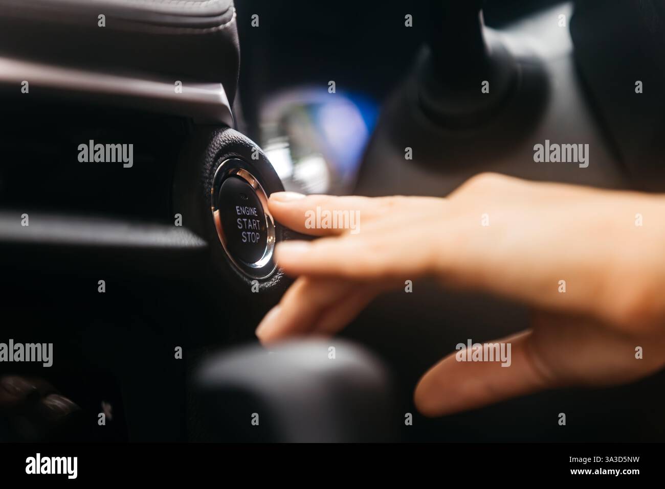 Primo piano di un pulsante di avviamento della vettura premuto da una donna. Concetto di tecnologia moderna, convenienza e innovazione nelle auto. Foto Stock