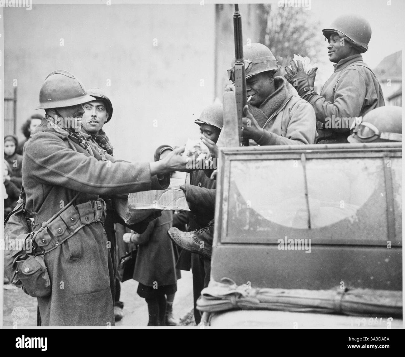 Seconda guerra mondiale - due soldati francesi sorridenti riempiono le mani dei soldati americani di caramelle, a Rouffach, Francia 1945 Foto Stock