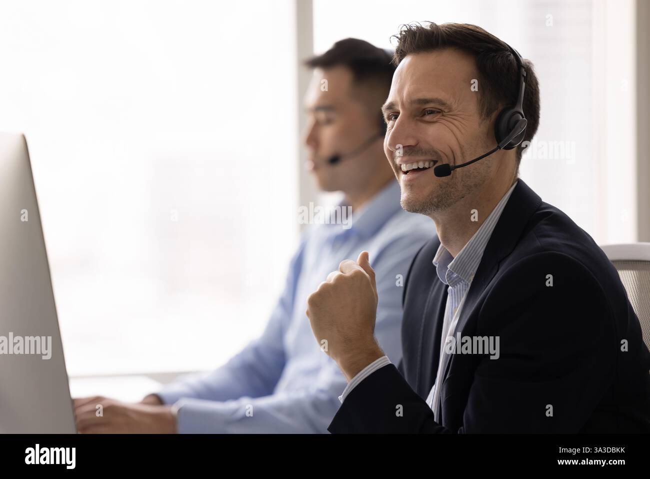 Allegro uomo del centro di supporto che indossa le cuffie e posa sul posto di lavoro Foto Stock