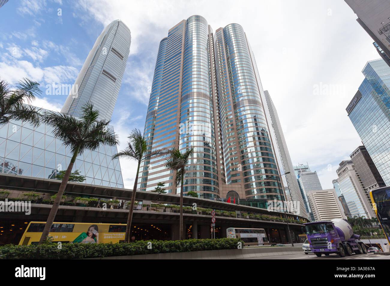Hong Kong - 15 luglio 2017: Paesaggio urbano con grattacieli alti sotto un cielo parzialmente nuvoloso, circondato da alberi lussureggianti, autobus pubblici, Foto Stock
