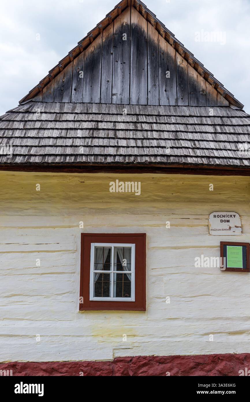 Vista frontale di una tradizionale casa in legno bianca con timpano in legno e piccola finestra a Vlkolinec, Slovacchia Foto Stock