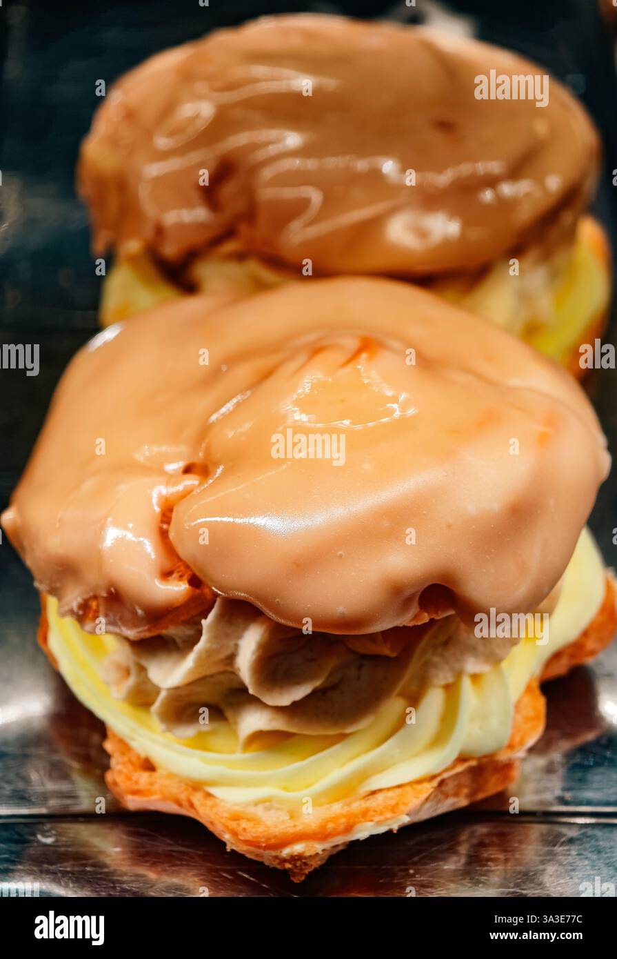 Ricchi Eclair ripieni di panna con glassa di cioccolato e caramello - dolci gourmet per gli amanti dei dessert - viziatevi con prelibatezze al forno - perfetti per celebrazioni e voglie dolci Foto Stock