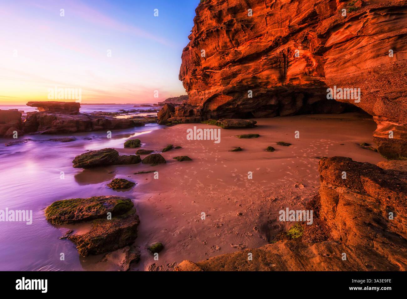 Grotta marina panoramica tra rocce di arenaria presso la cittadina costiera di Caves Beach, Austrlia, sull'oceano Pacifico all'alba. Foto Stock