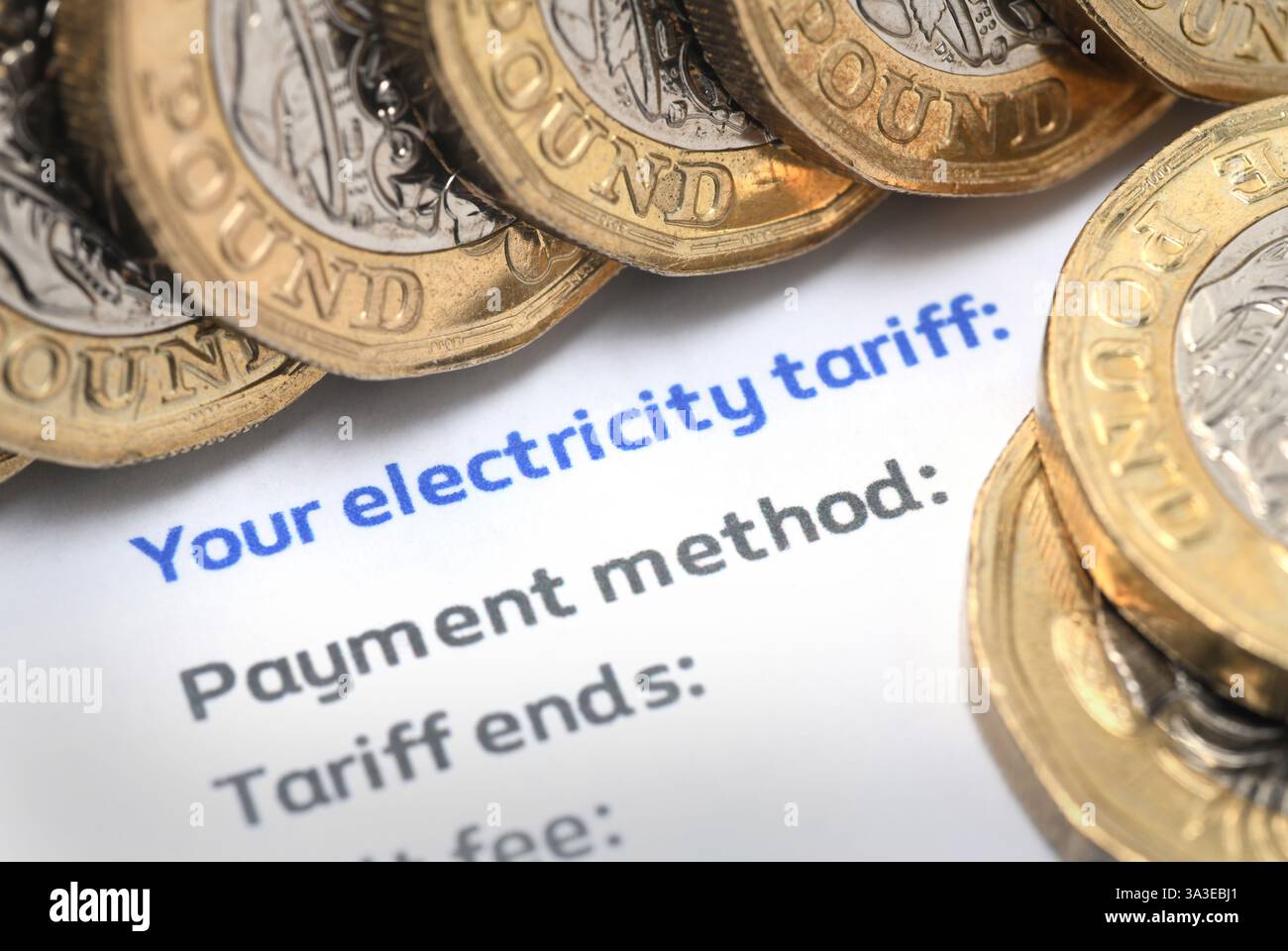 BOLLETTA DELL'ELETTRICITÀ CHE MOSTRA "LA TUA TARIFFA DELL'ELETTRICITÀ" CON MONETE DA UNA STERLINA RE BOLLETTE DELL'ENERGIA RISCALDAMENTO ABITAZIONI CARBURANTE POVERTÀ ETC UK Foto Stock