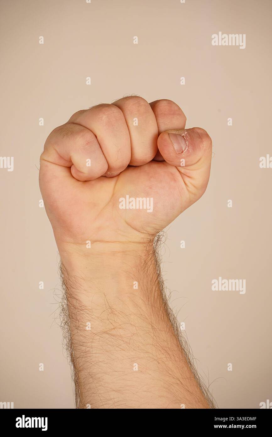 La mano forma un pugno forte, simboleggiando forza e protesta. Questo gesto iconico parla di spirito combattivo. Lo sfondo semplice migliora il Foto Stock
