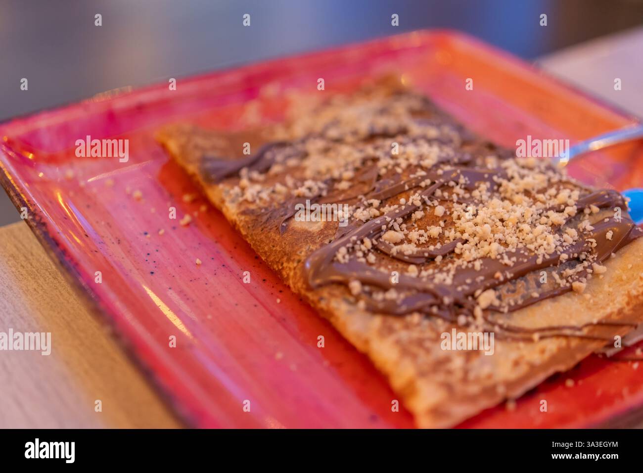 Deliziosa crema alla Nutella su un piatto rosa. Crepe Delight: Dolce esperienza con cioccolato e noci Foto Stock