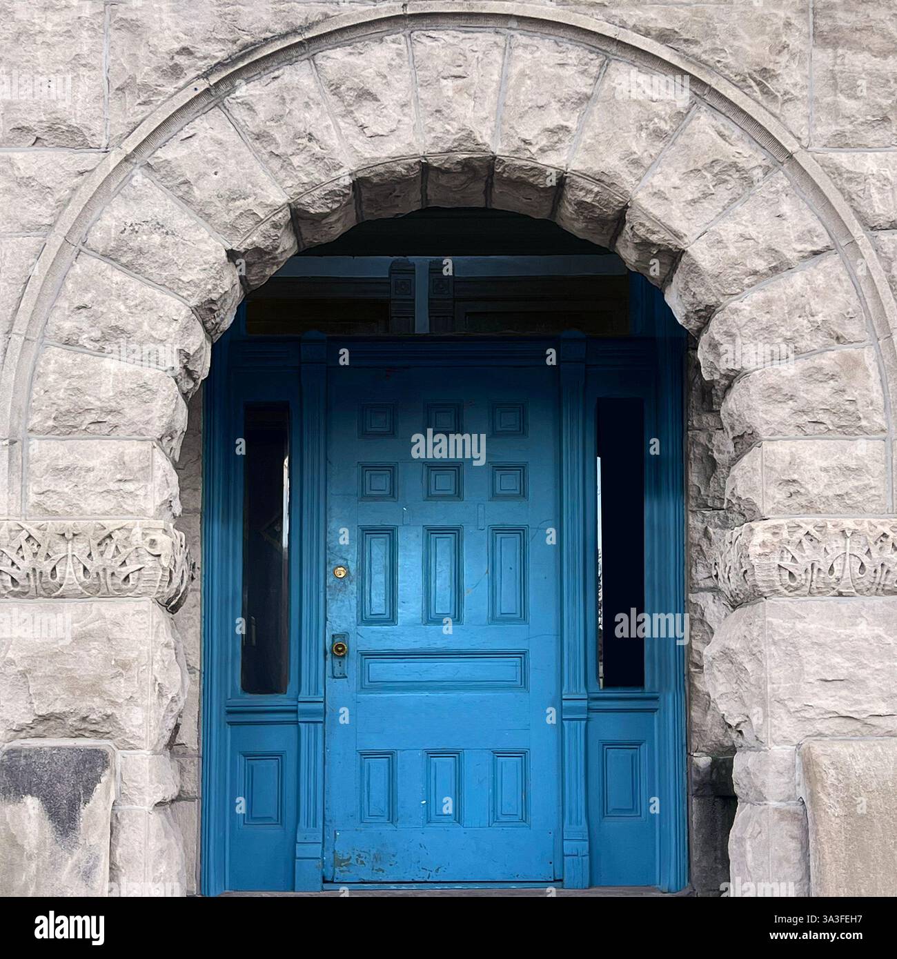 Porta in legno blu posta all'interno di una storica arcata in pietra, caratterizzata da intricati dettagli architettonici. - Immagine stock catturata con smartphone