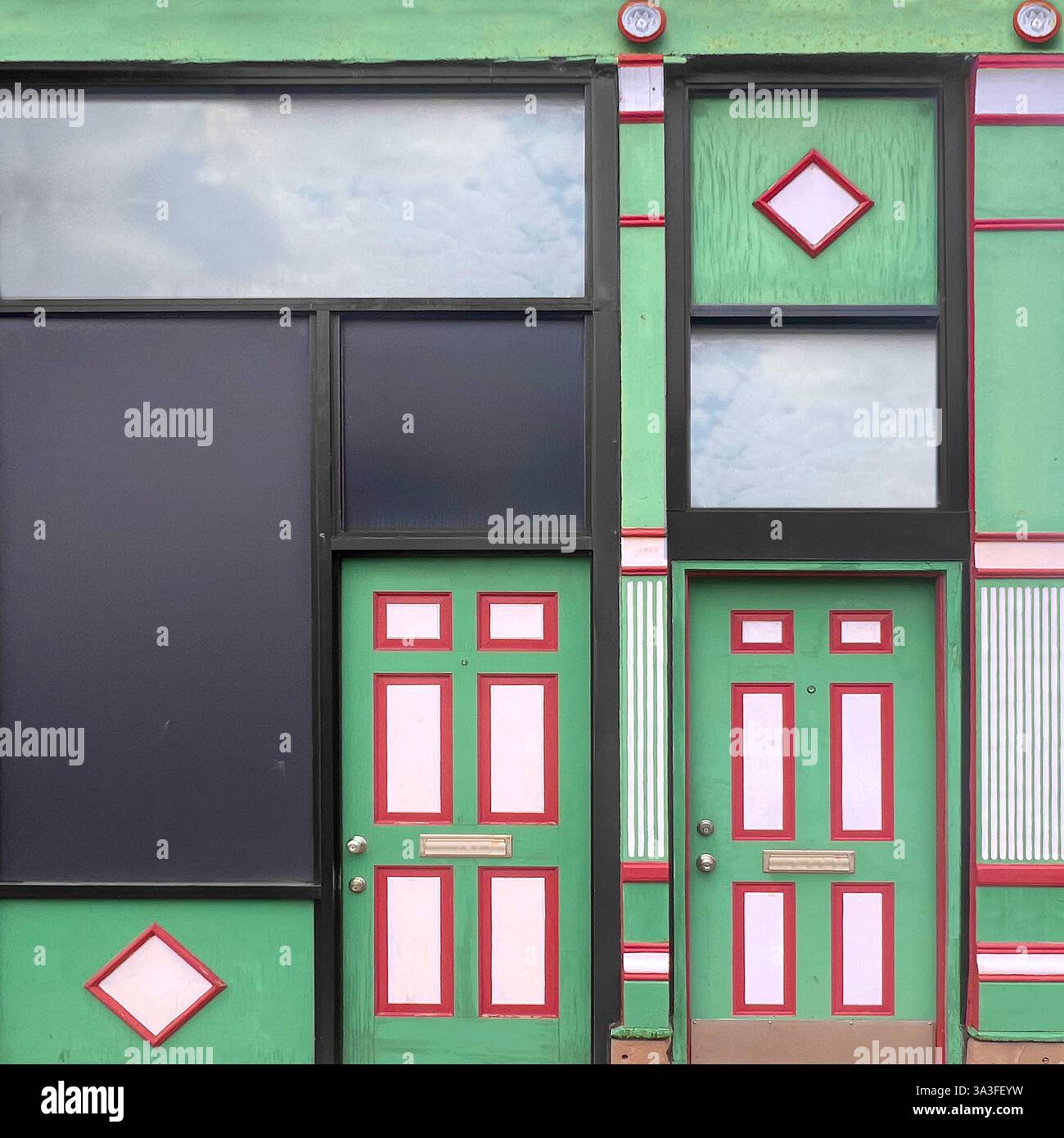 Vetrina verde e rossa con doppi sportelli simmetrici caratterizzati da elementi decorativi geometrici che creano un'impressionante composizione architettonica Foto Stock